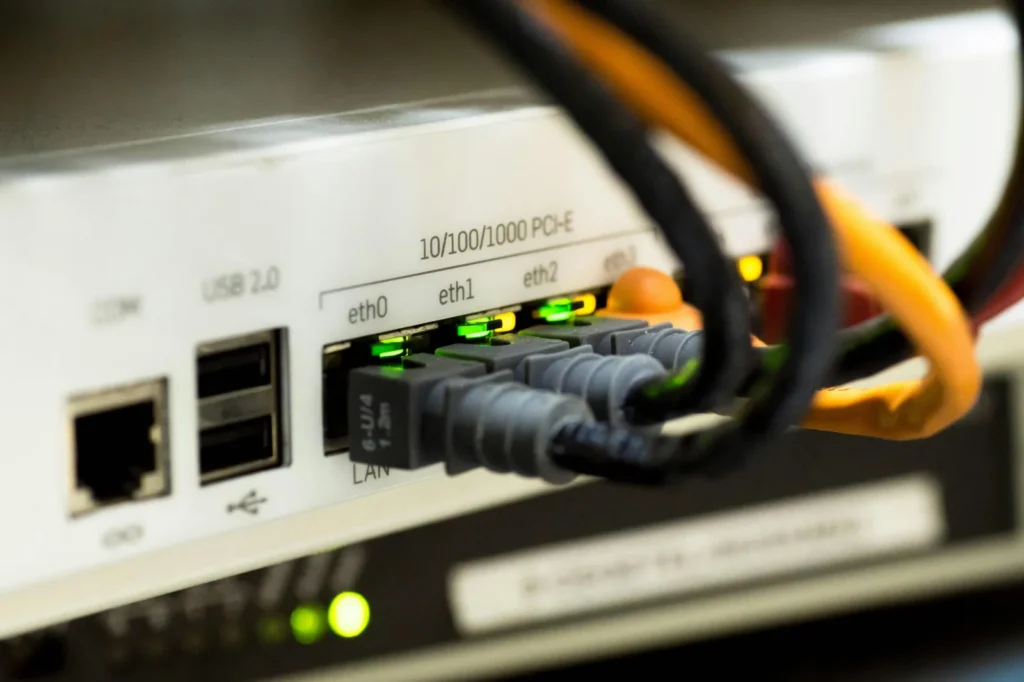 Zbliżenie portów ethernetowych urządzenia sieciowego z podłączonymi kablami krosowymi i zapalonymi diodami